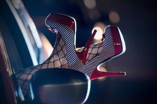 Eine Prostituierte streckt ihre High-Heels mit roten Bleistiftabsätzen aus einem Autofenster. 