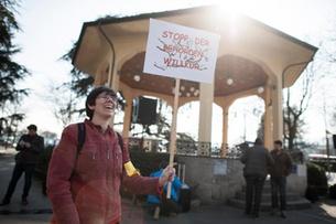 Eine Demonstrantin hält ein Schild mit 'Stopp der Behördenwillkür'